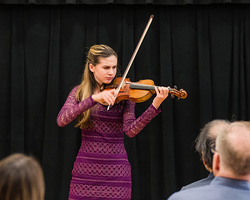 Student playing violin in a recital.