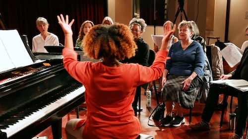 Alison Crockett leading singers of the Capital City Voices in song.